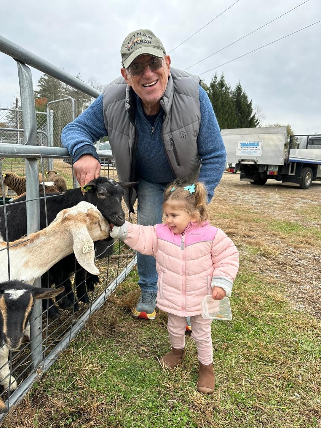 Man and child feeding goats at the farm