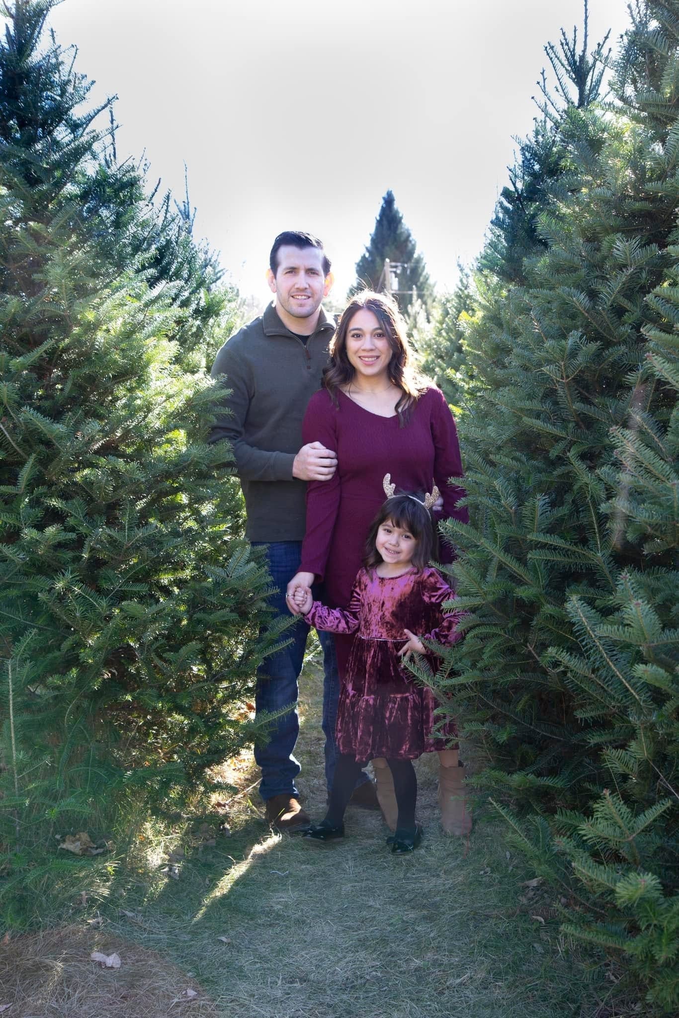 Family portrait standing between Christmas trees